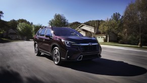 A dark red 2022 Subaru Ascent driving down a winding road.