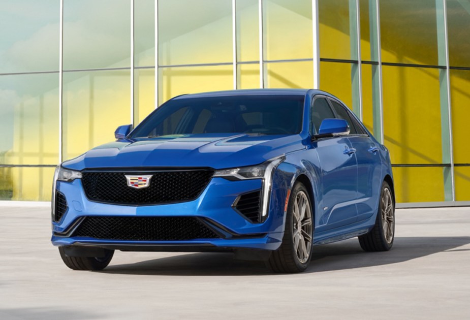 The front 3/4 view of a blue 2023 Cadillac CT4-V in front of a glass building facade