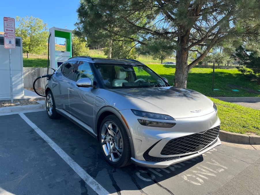 The 2023 Genesis GV60 plugged into an Electrify America charger.