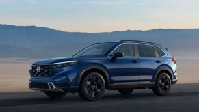 A blue 2023 Honda CR-V small SUV is driving on the road.