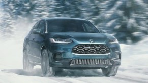 A green 2023 Honda HR-V subcompact SUV is driving in the snow.