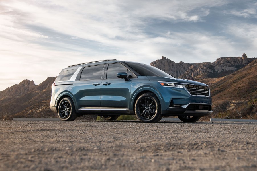 A blue 2023 Kia Carnival in a desert area.