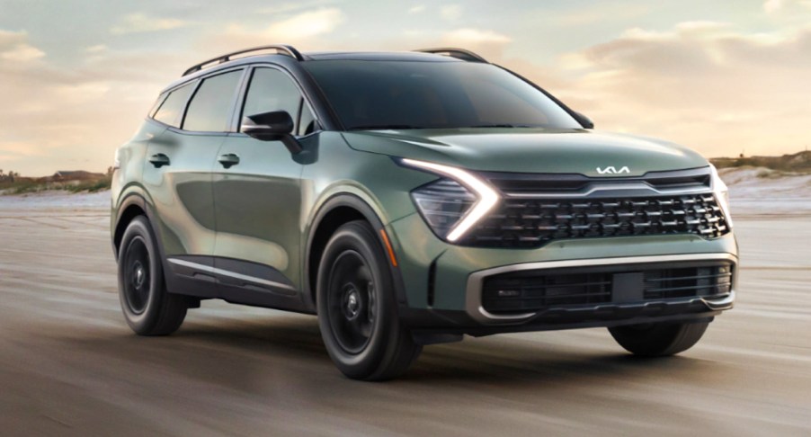 A green 2023 Kia Sportage small SUV is driving on the road.