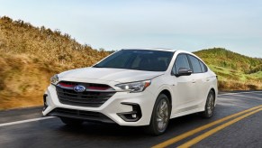 A white 2023 Subaru Legacy driving down the road.