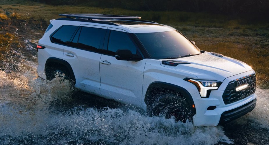 A white 2023 Toyota Sequoia full-size SUV is driving in the water. 