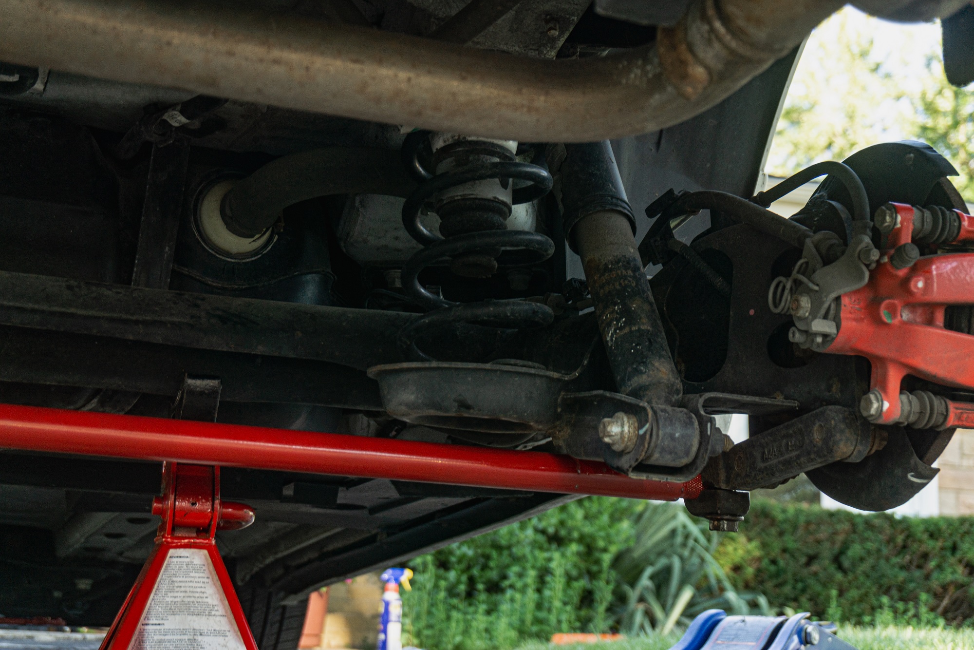 The passenger's side bracket of a red Neu-f rear torsion bar on a 2013 Fiat 500 Abarth