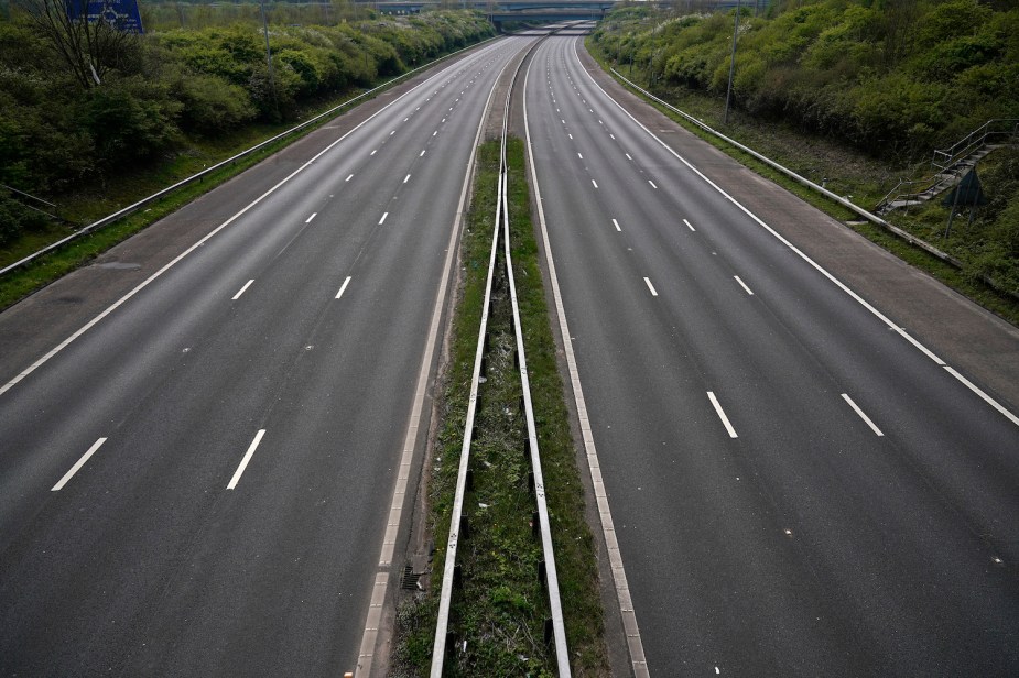 An empty multi-lane interstate highway, a bridge visible in the distance.