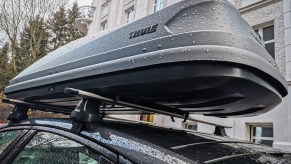 A grey cargo roof box on top of a car with roof racks.