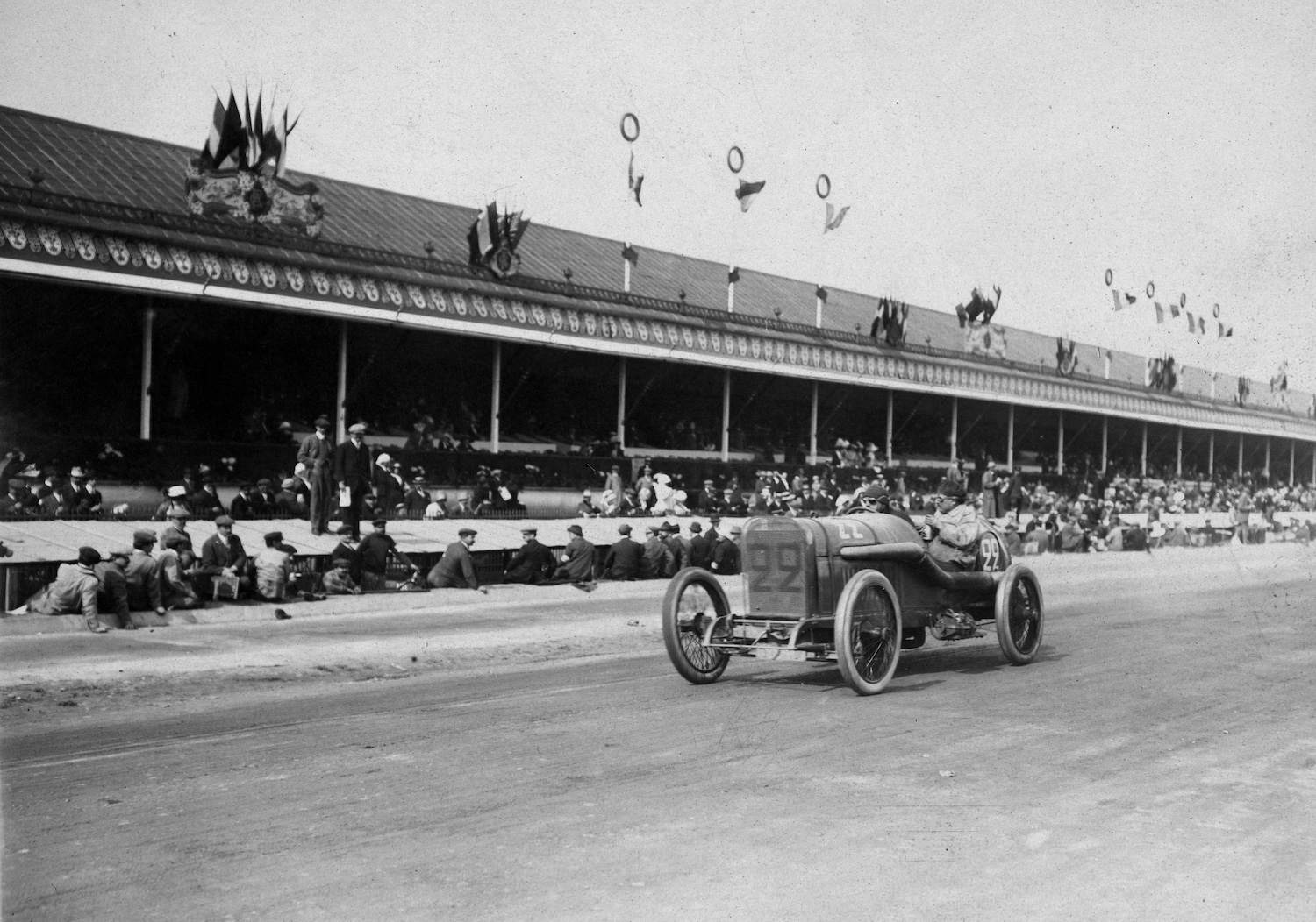 A Peugeot race car on a dirt track winning the French Grand Prix with the world's first DOHC engine.