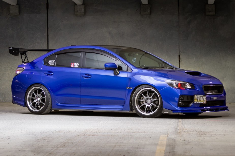 A blue Subaru WRX with its badges removed, parked in an indoor lot.