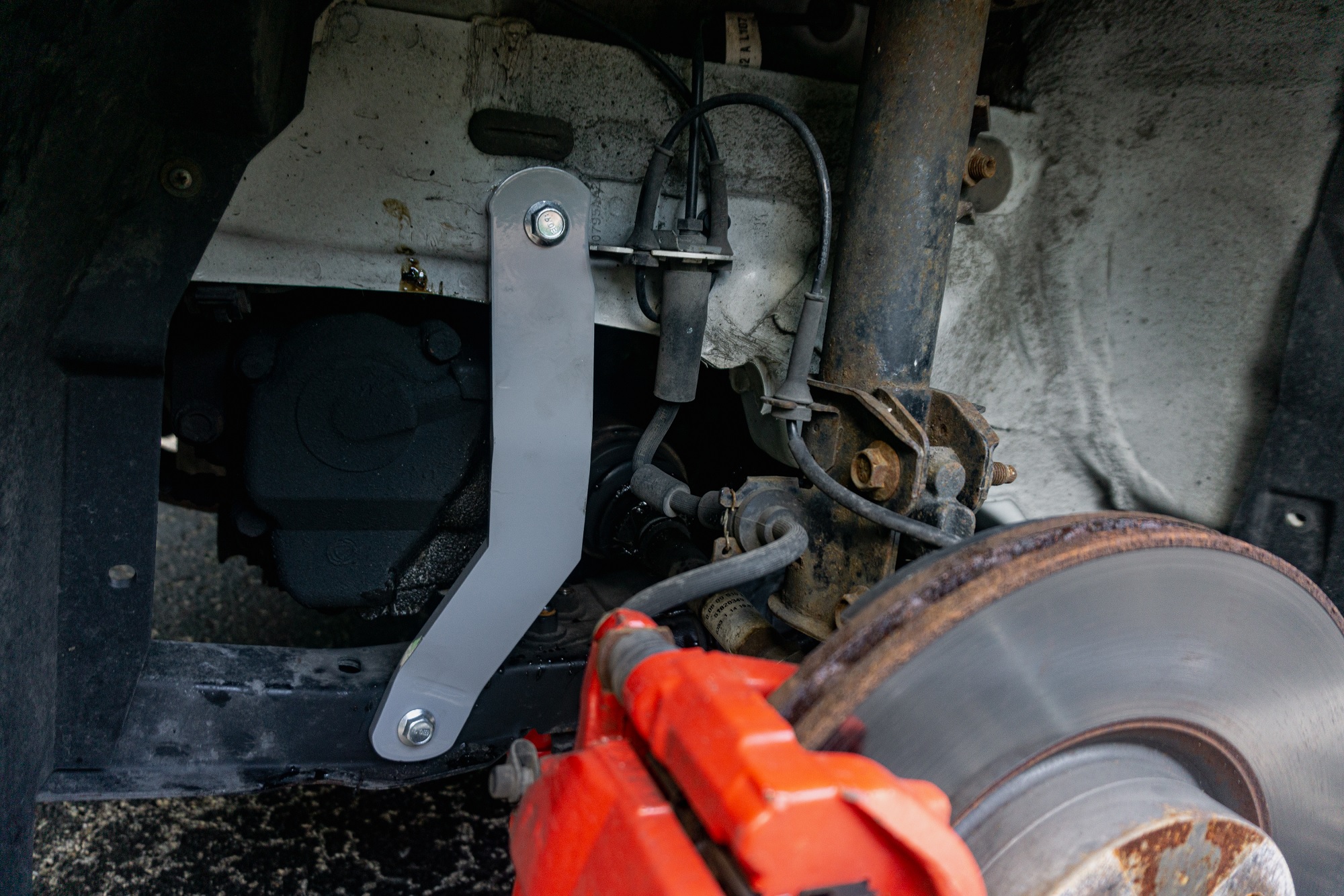 A gray El Gato Engineering chassis brace on the driver's side of a white 2013 Fiat 500 Abarth