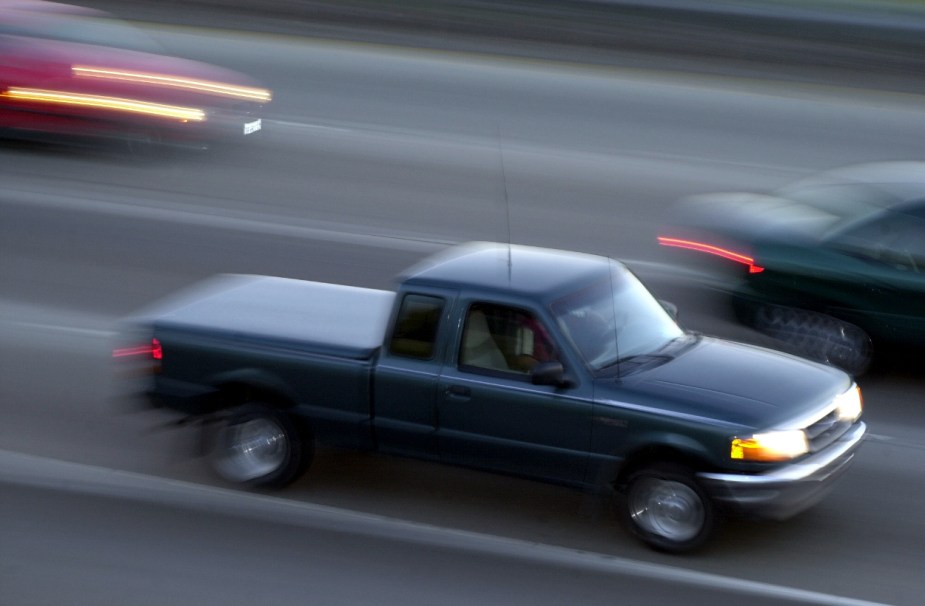 An old Ford Ranger drives on the road.