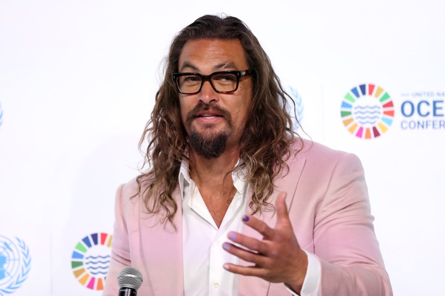 Jason Momoa, whom recently had a collision with a motorcyclist, wearing a pink suit and white button-up shirt.