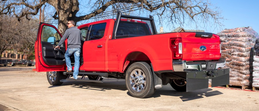 Red Ford pickup truck wearing wide rubber mud flaps.