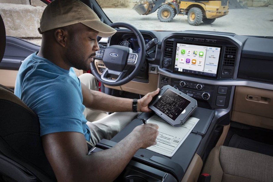 Man using tablet in Ford F-150, highlighting how to remove personal information from a car to avoid identity theft 