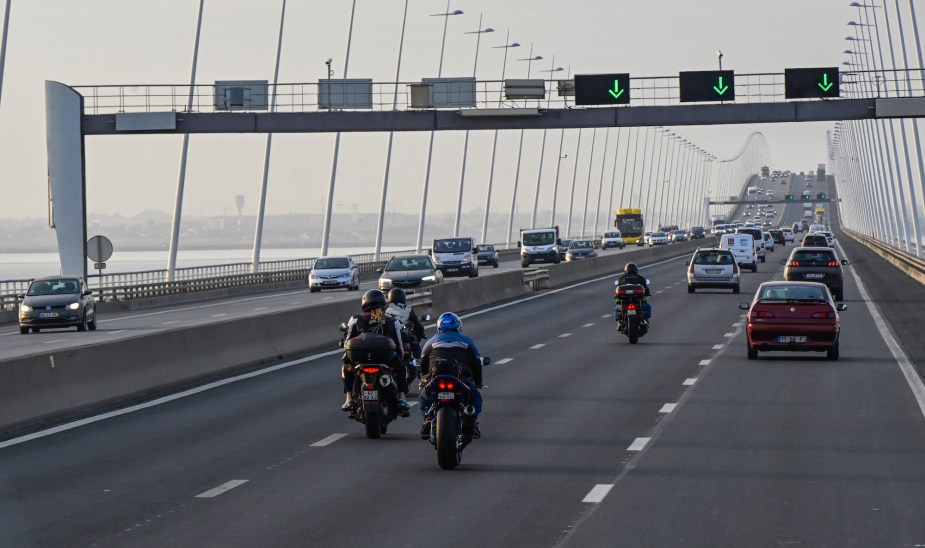 People riding a motorcycle in high winds potentially across a bridge. 