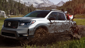 A 2023 Honda Ridgeline off-roads with a dirt bike in its bed.