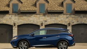 A blue 2023 Nissan Murano parked in front of a four car garage