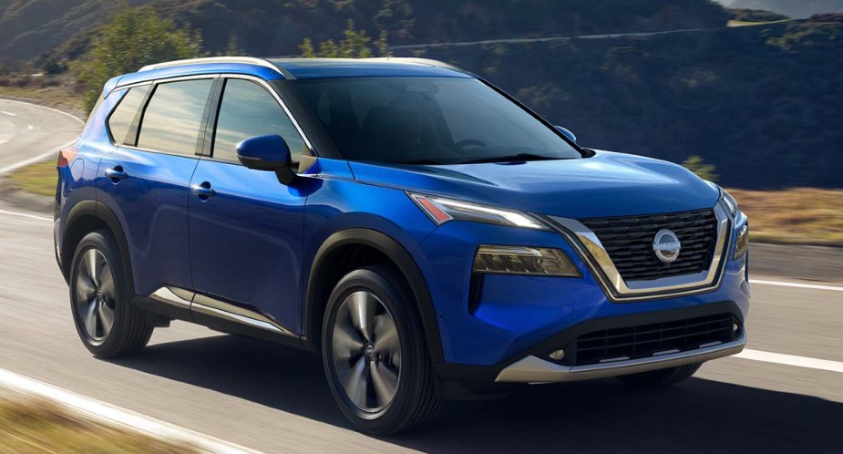 A blue 2022 Nissan Rogue compact SUV is driving on the road.