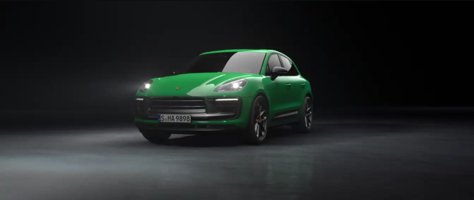 A green 2023 Porsche Macan luxury compact SUV promotional photo in a dark black void