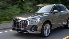 A gray 2022 Audi Q3 driving down a tree-lined road.