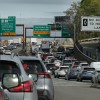 A Boston highway packed with standstill traffic, exit signs for Cambridge visible in the background.