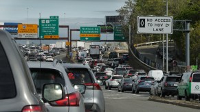 A Boston highway packed with standstill traffic, exit signs for Cambridge visible in the background.