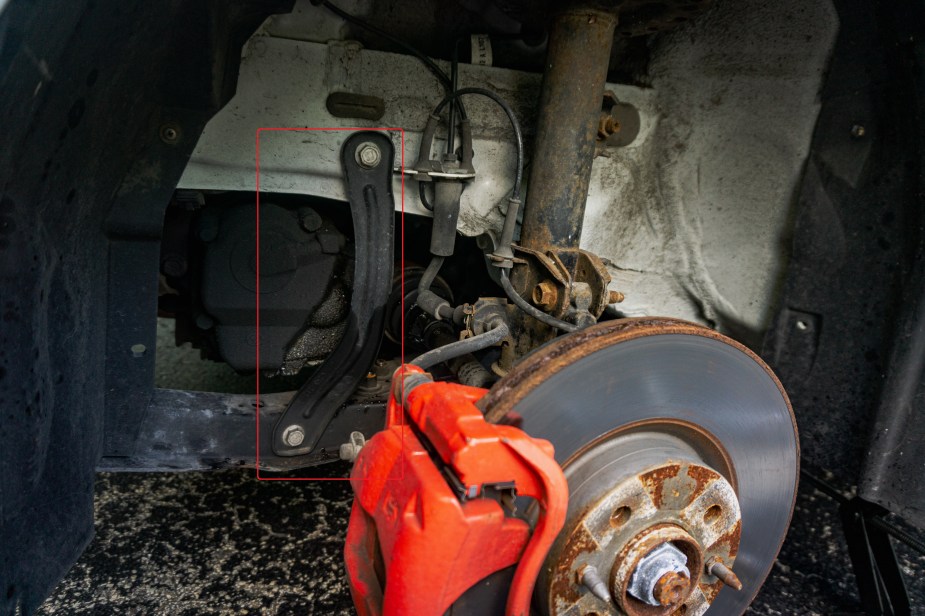 A stock black front subframe chassis brace on a white 2013 Fiat 500 Abarth highlighted in red