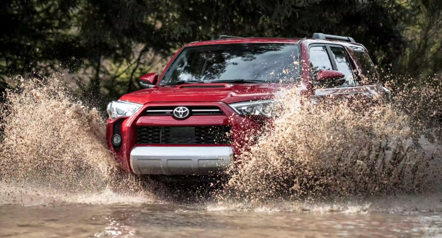 A red 2022 Toyota 4Runner midsize SUV is driving off-road.