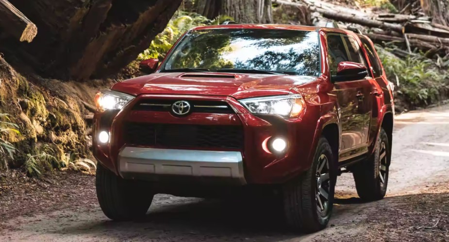 A red Toyota 4Runner midsize SUV is driving on the road.