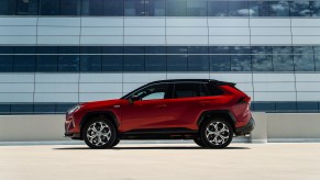 A red Toyota RAV4 Prime Small SUV parked near an office building