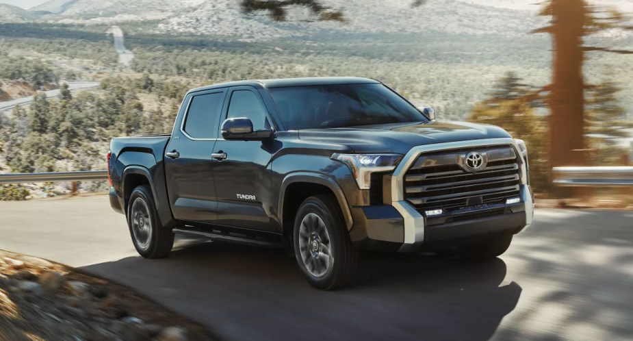 A black 2022 Toyota Tundra full-size pickup truck is driving on the road. 