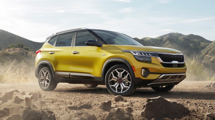 Yellow 2023 Kia Seltos crossover SUV parked near some rocks