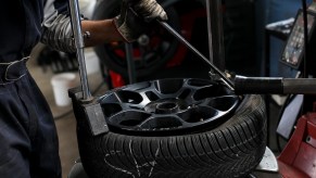 A car tire being installed on a giant rim.