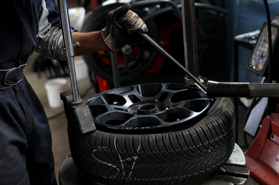 A car tire being installed on a giant rim. 