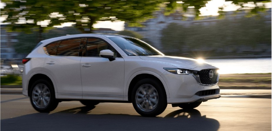 A white 2022 Mazda CX-5 driving through a town. 