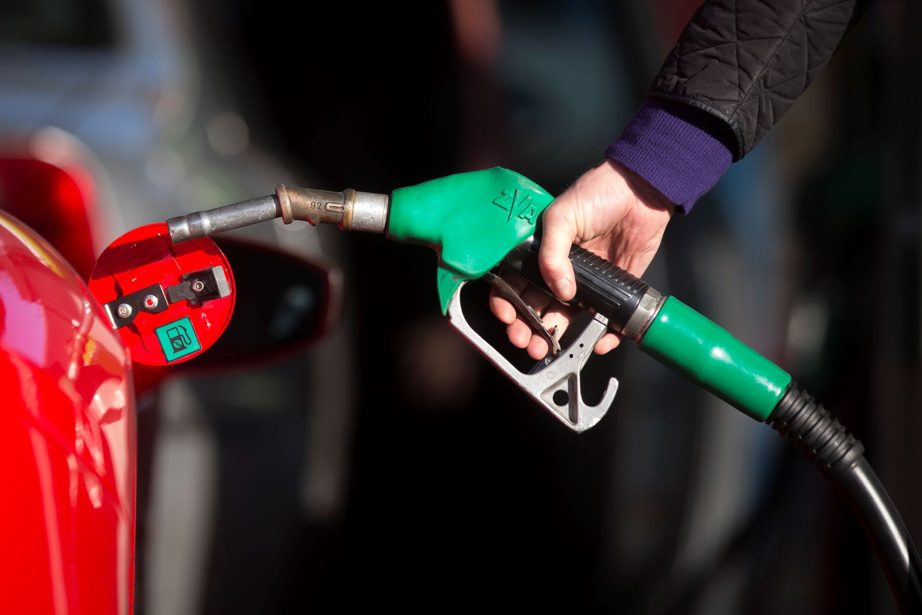 A man filling up his luxury Ferrari vehicle with premium fuel at a petrol gas station in Guildford, U.K.