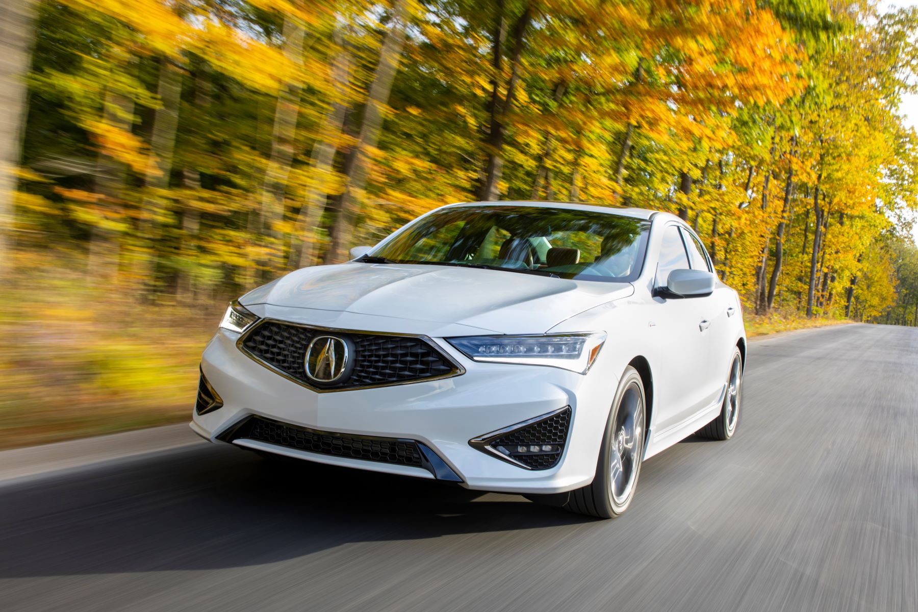 A white 2021 Acura ILX A-Spec compact luxury sedan/executive car driving near a yellow leaf forest of trees