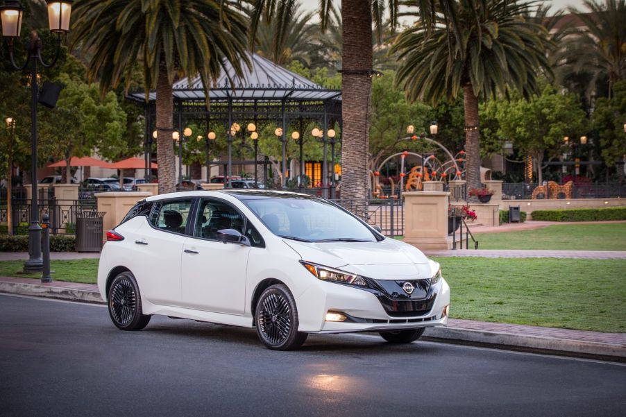 A white 2023 Nissan Leaf all-electric (EV) hatchback model parked near a gazebo