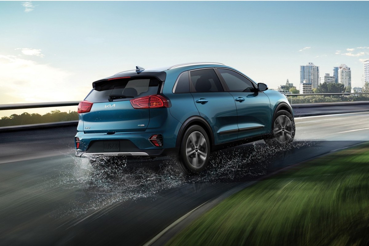 A blue Kia Niro driving on a wet road. 