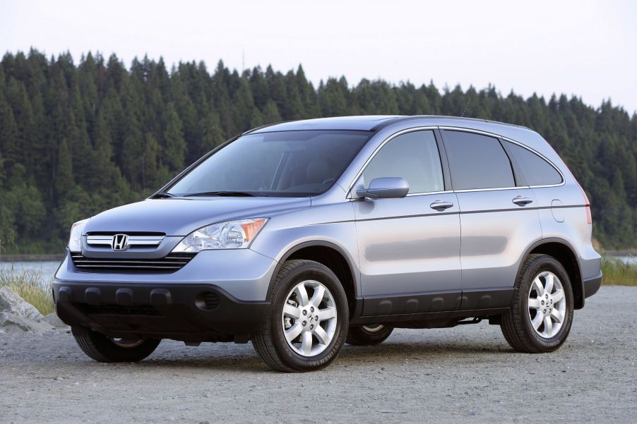 A silver gray 2007 Honda CR-V EX-L with Navigation compact SUV model parked on sand near a river and forest