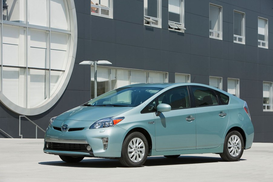 A light green 2015 Toyota Prius Plug-in parked in front of a building