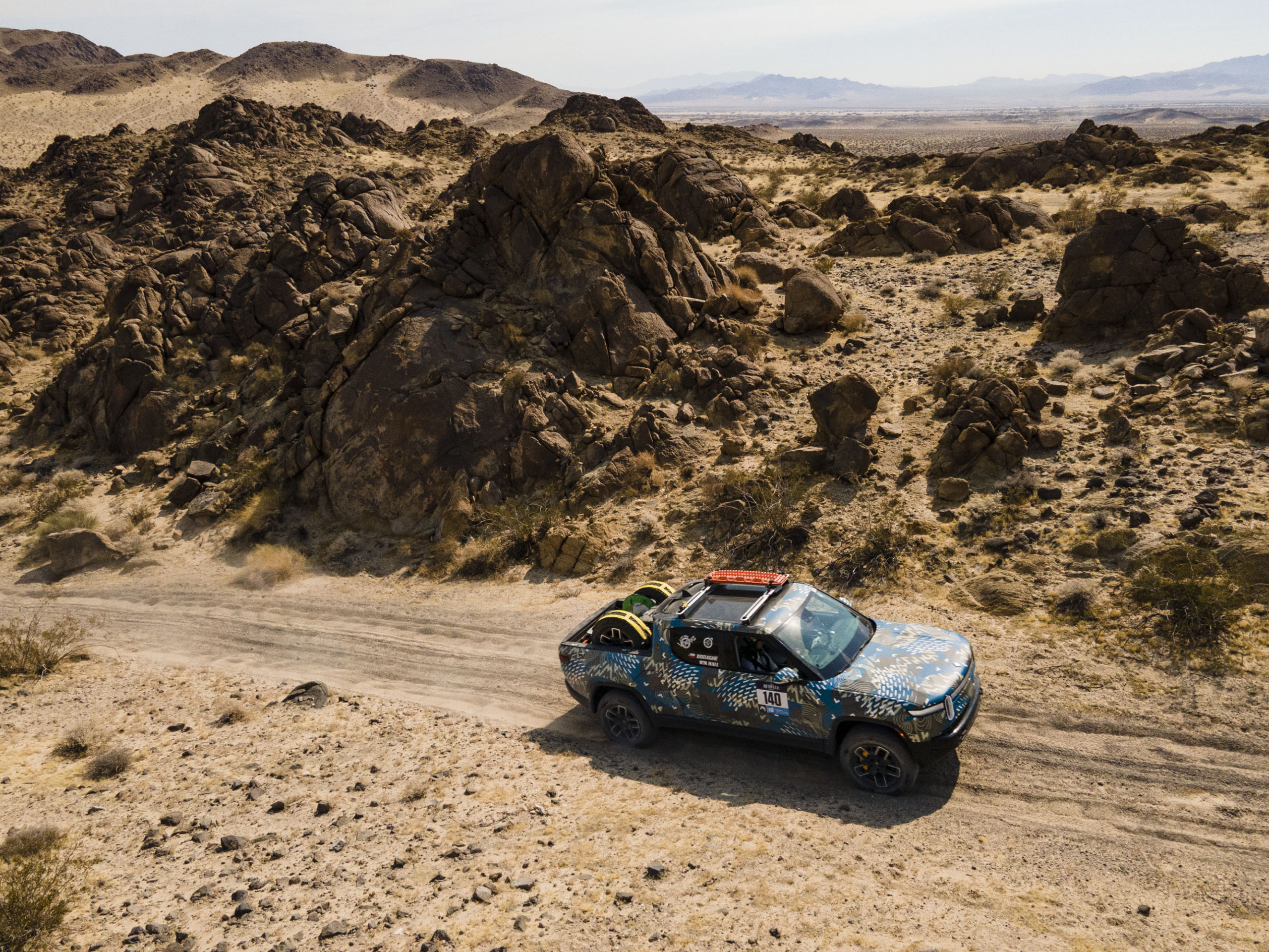 Rivian electric truck navigating an off-road trail.