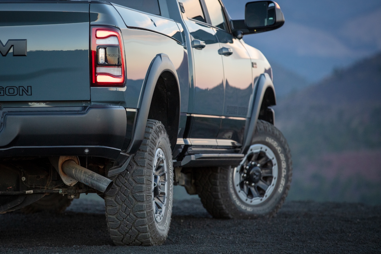 Closeup of a blue-gray Power Wagon pickup truck parked on a mountain pass, trees visible in the distance.