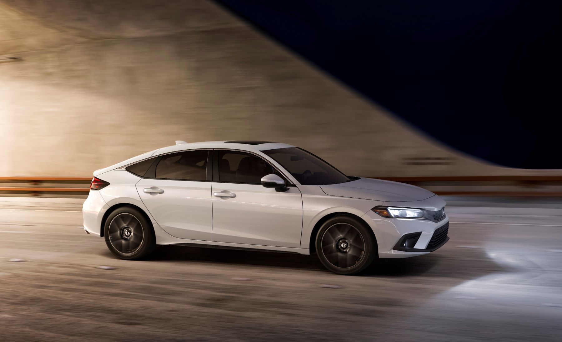 A white 2022 Honda Civic Hatchback model driving through a tunnel