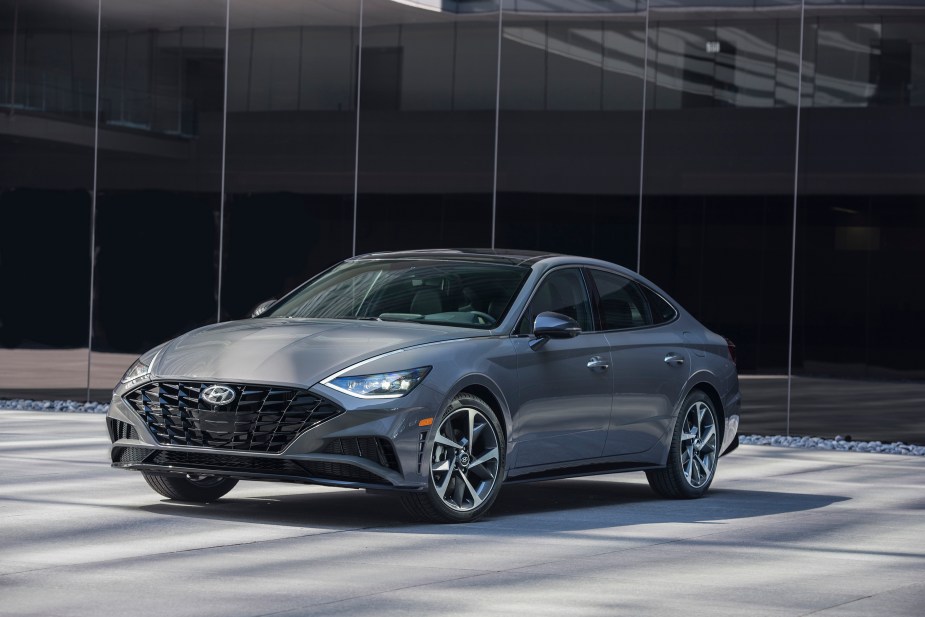 A silver 2022 Hyundai Sonata Hybrid is shown at 3/4 view with a glass-walled city building in the background.