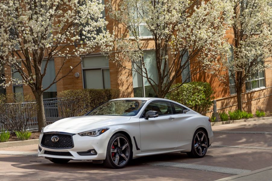 A white 2022 Infiniti Q60 luxury sports coupe model parked on a cobblestone street