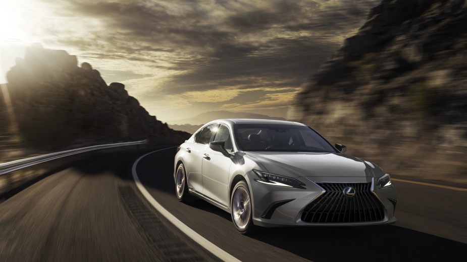 A silver 2022 Lexus ES Hybrid drives down a road.