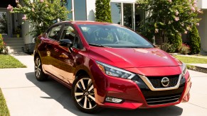 A red 2022 Nissan Versa subcompact car parked in front of a garage