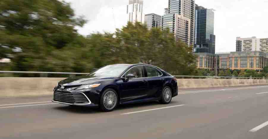 A black 2022 Toyota Camry AWD Sedan driving down a highway